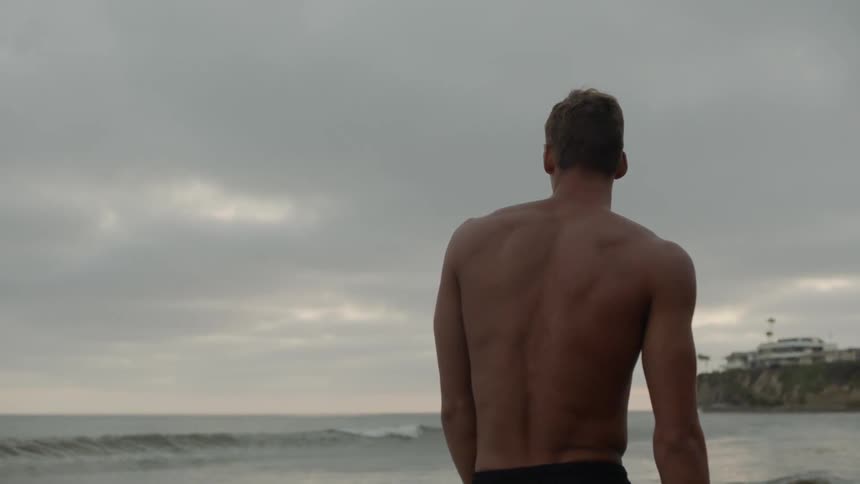 A man is standing in the sand of the beach
