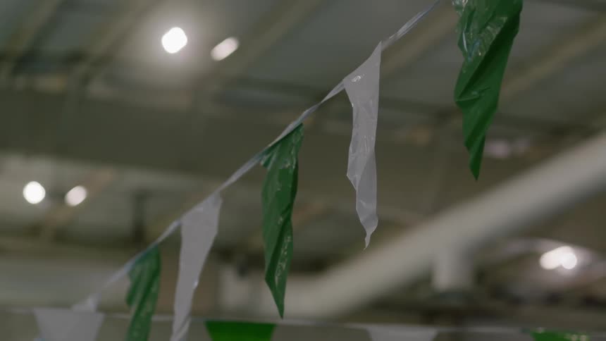 Small green and white flags are strung across a large room