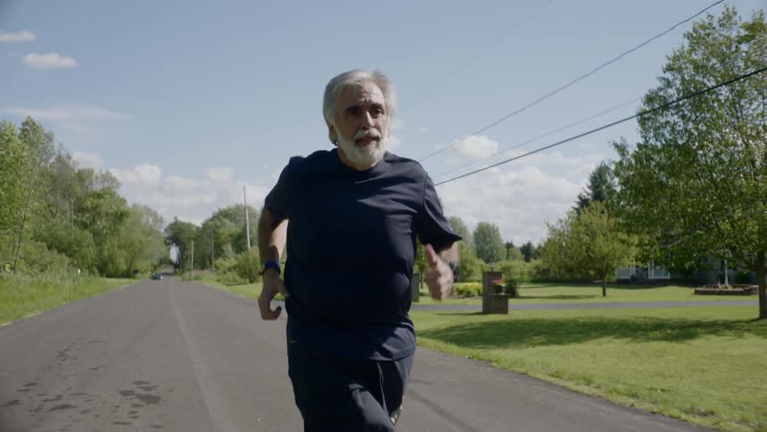 Elderly man jogging on a neighborhood road in the country