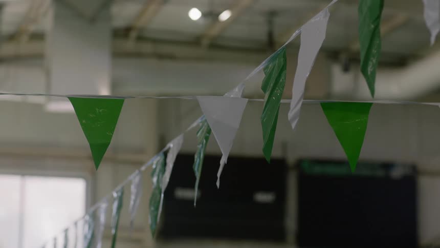 Green and white plastic flags hang on two lines in a large interior space