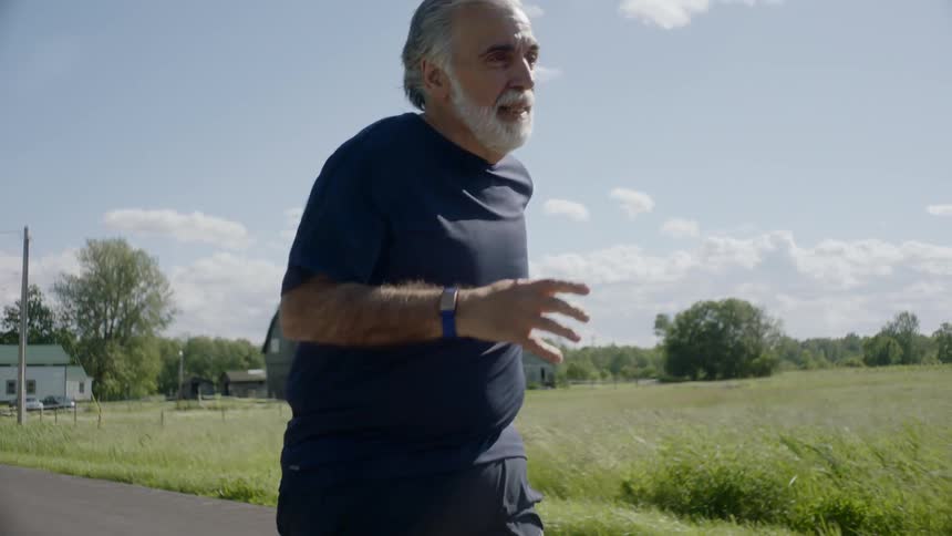 Senior bearded man runs on the road in the countryside
