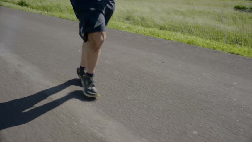 A heavy set man jogs down a road