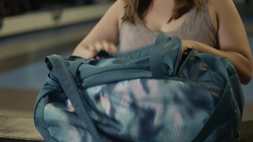 Woman puts the bag on the table and takes out a white towel in the gym
