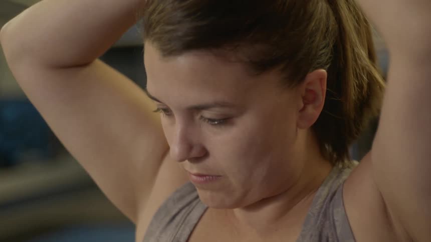 A woman tying her hair into a bun
