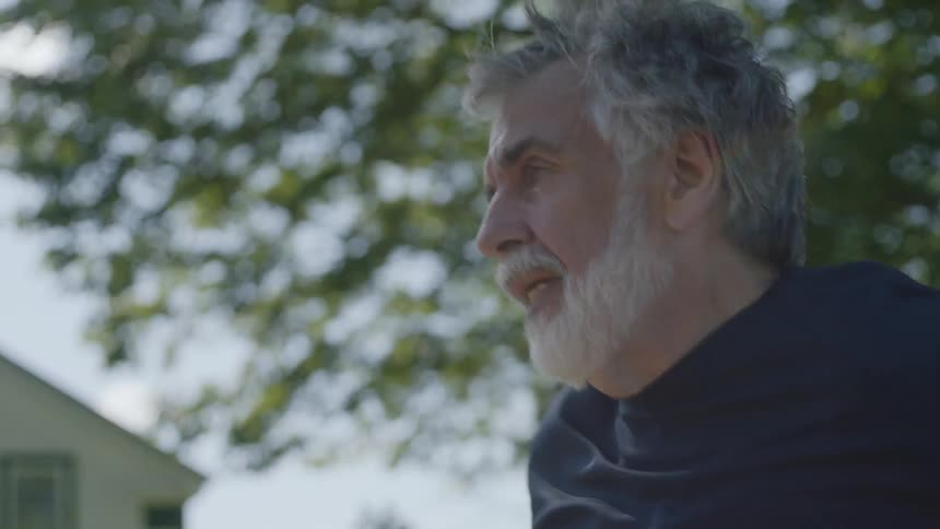 Bearded senior man runs on the road on a sunny day