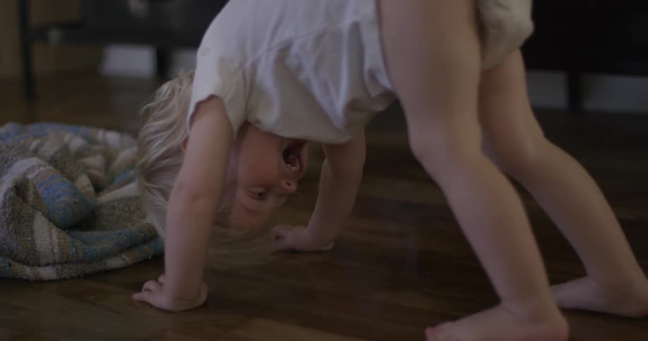 A woman and toddler bent over with their hands placed on the floor