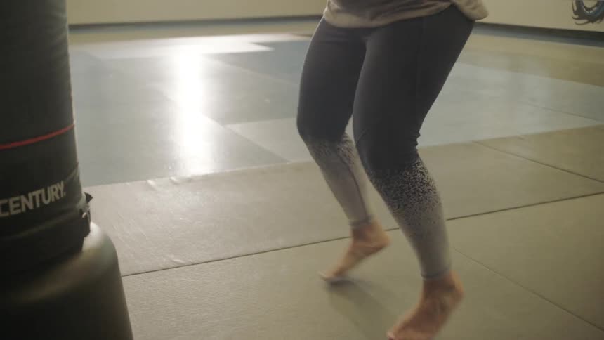 A woman wearing boxing gloves doing cardio exercises in a gym