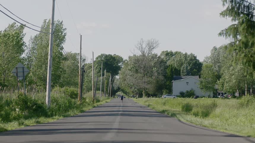 A person runs down the middle of a road in a rural neighborhood
