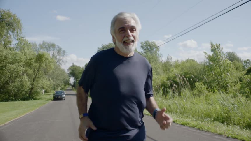 An older man jogs down the middle of a road