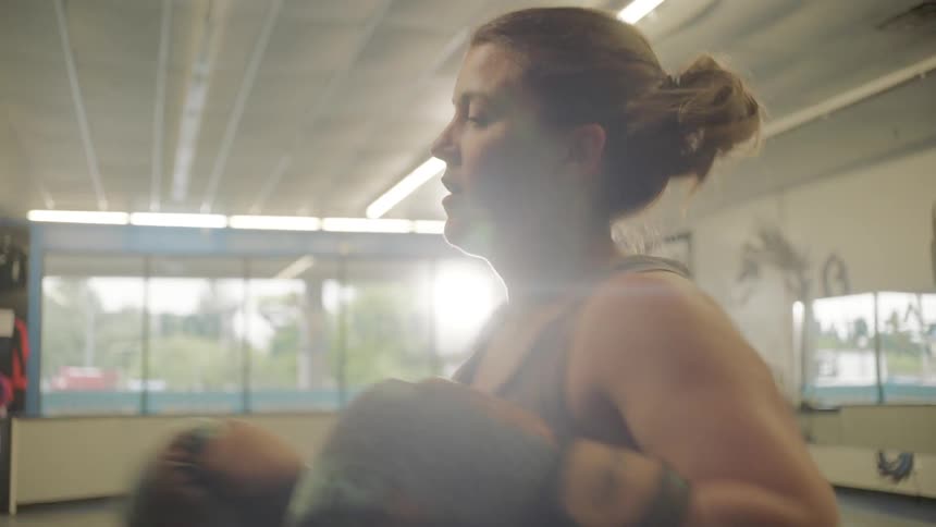 A woman in an indoor gym punching a heavy bag