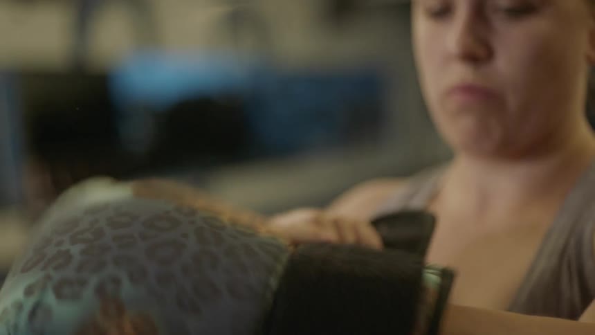 A woman puts on boxing gloves in a gym