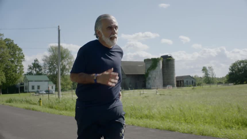 Senior bearded man runs on the road during daylight