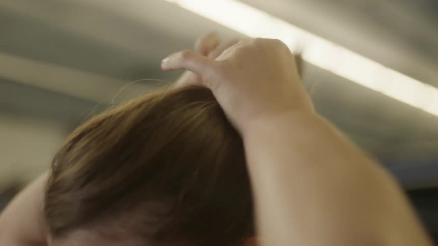 A woman is putting her hair in a ponytail