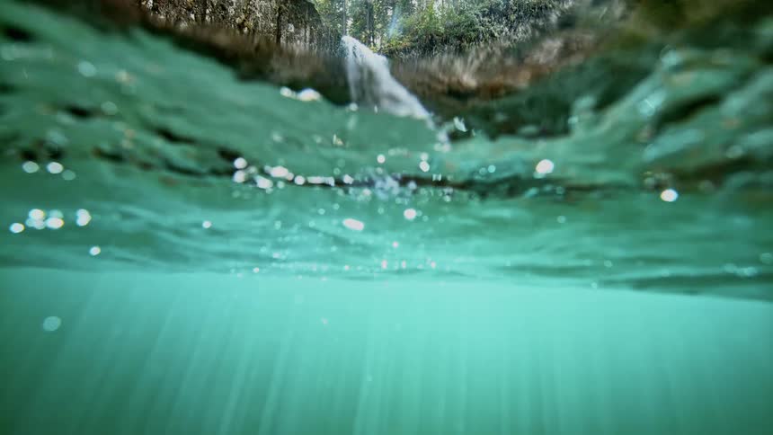 A waterfall flows down the side of a cliff in to the water below