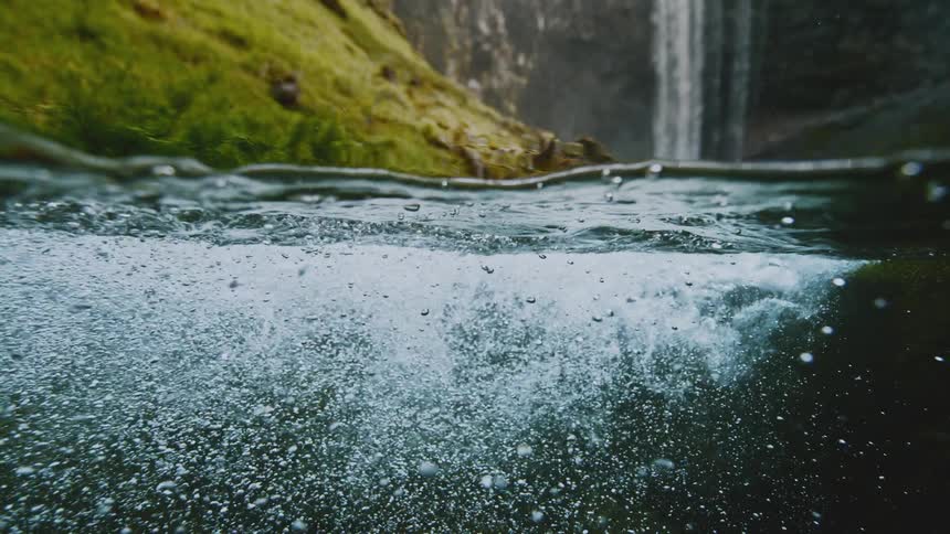 The water in the stream moves around as the waterfall pours