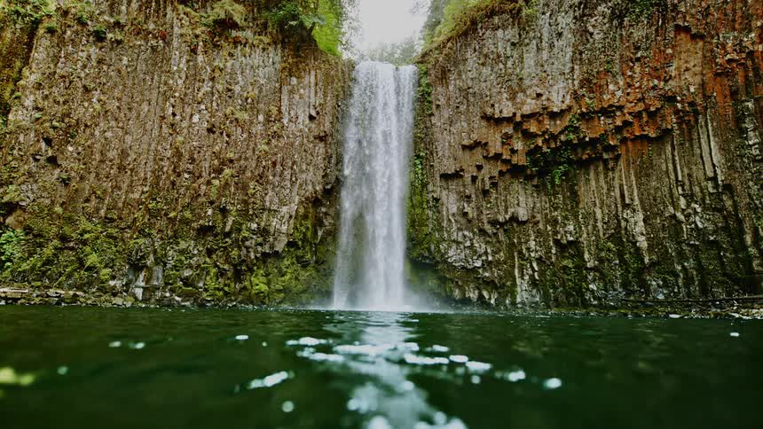 Waterfall rushing down from a cliff into a swimming hole