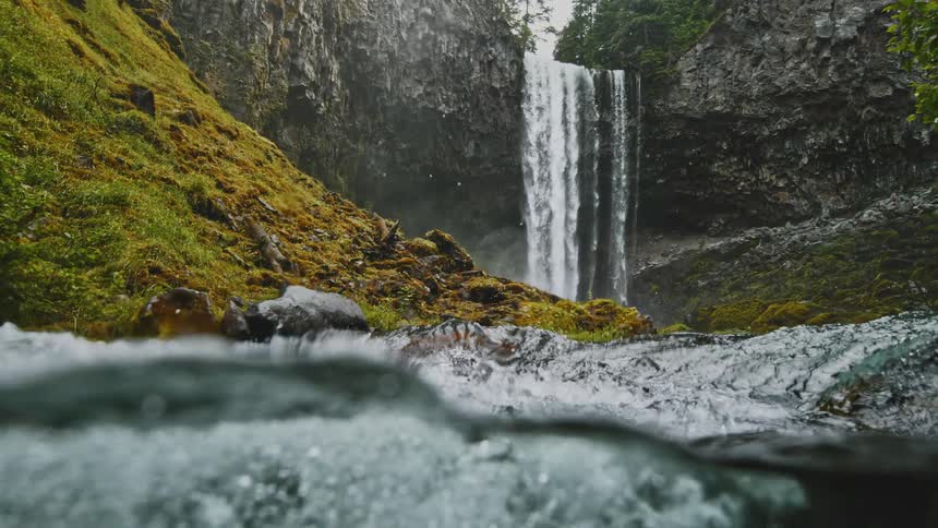 Water drops from a flowing waterfall splash onto the river surface