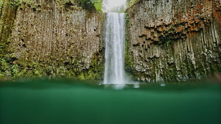 The waterfall is falling from the cliff into the spring
