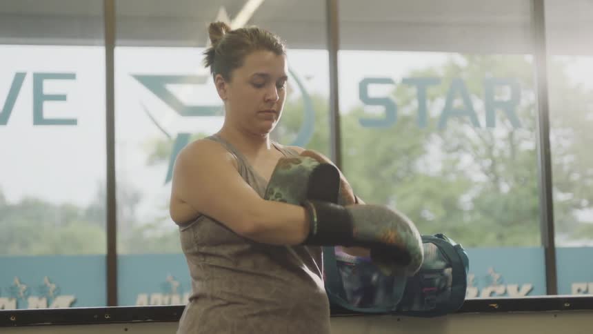 Woman puts on boxing gloves in gym