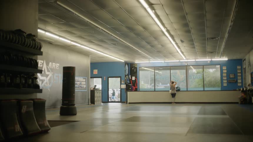A woman stands at the window in a commercial space and puts her up into a ponytail