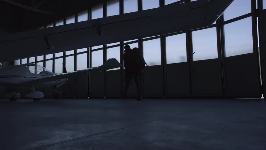 A person carrying a large backpack walking through an airplane hangar