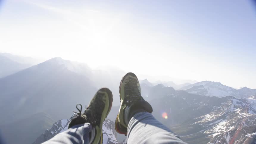 A persons legs up in the air with the snowy mountains in the background