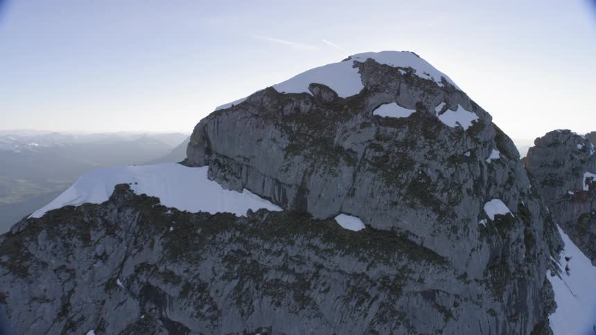 Sun shines from behind snow cover mountain top