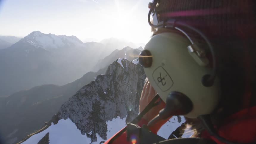 A photographer takes photos of snowy mountains from a helicopter
