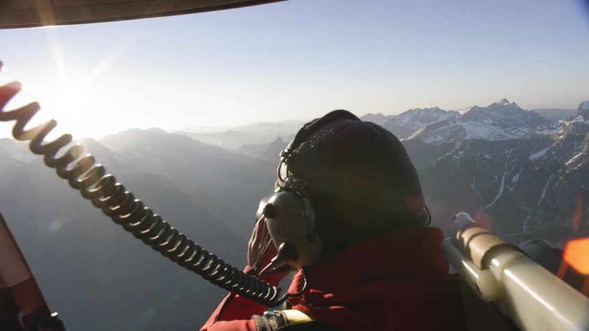 A photographer taking photos from the open door of a flying helicopter