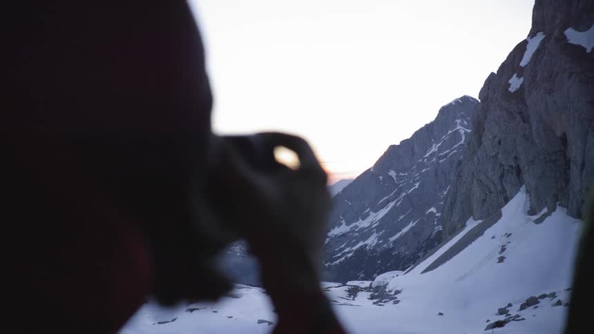 Woman takes a photo of the snow covered mountains