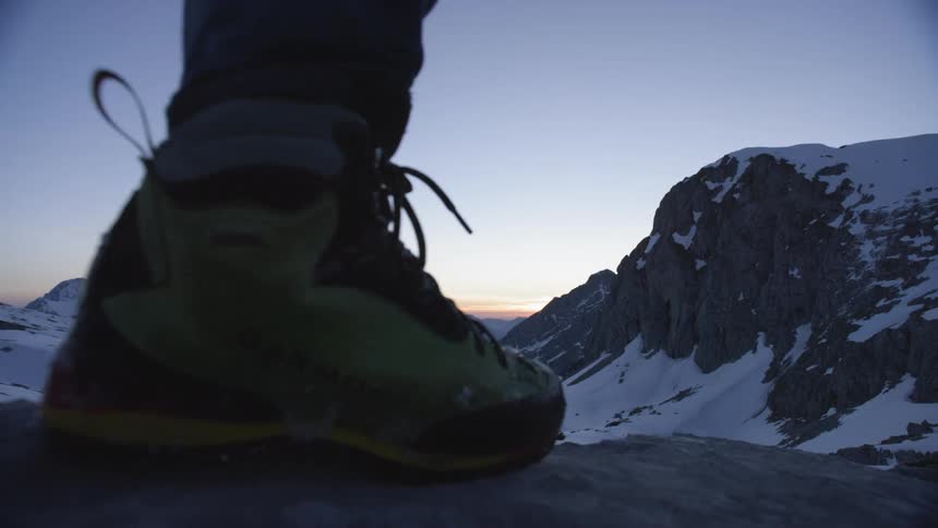 A person is hiking on the top of the mountains at sunset