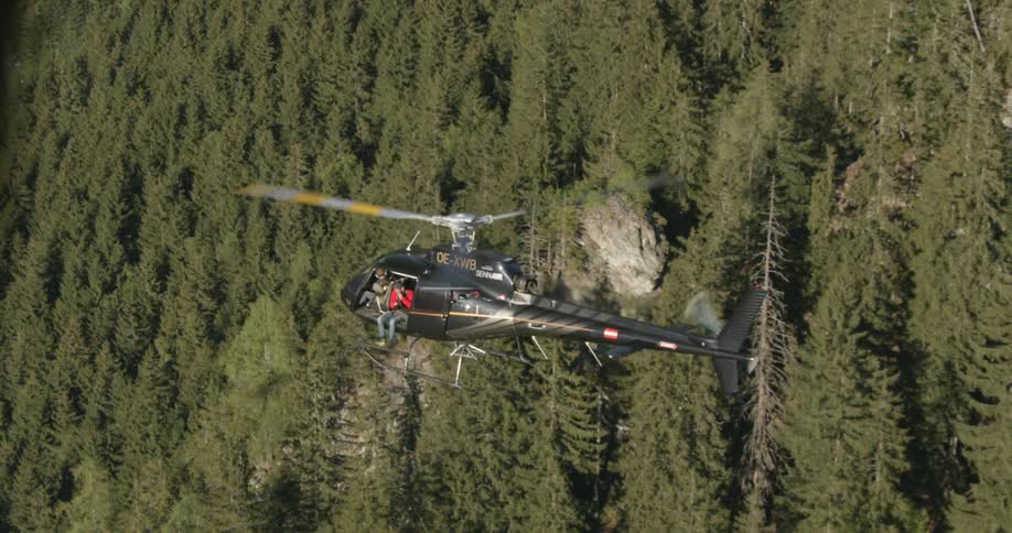 A helicopter is flying over a forest area