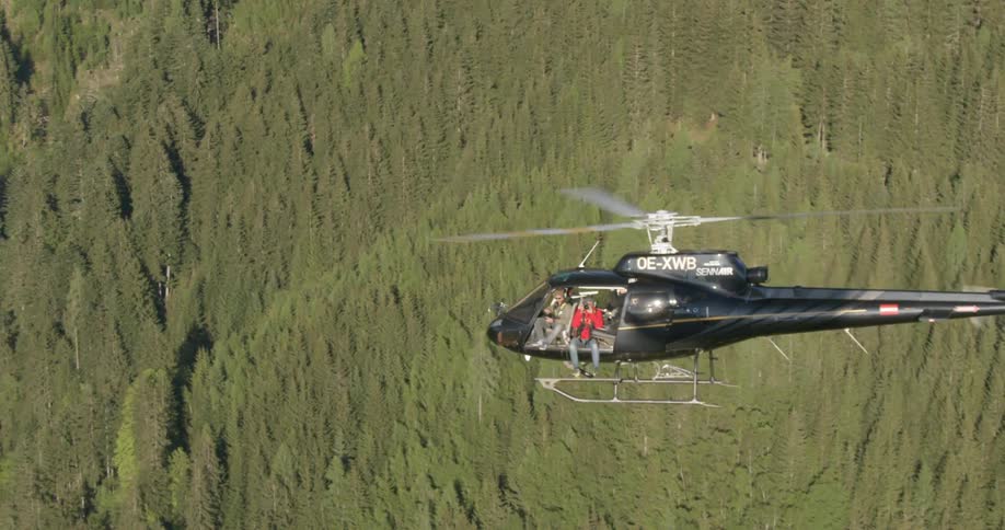 A helicopter is flying over a forest