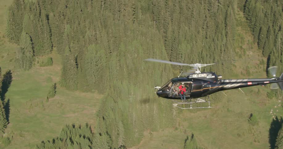 A helicopter flying over a forest during the day