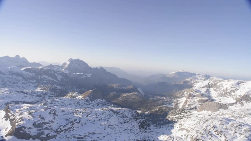 A snowy cliff with snow covered mountains in the background