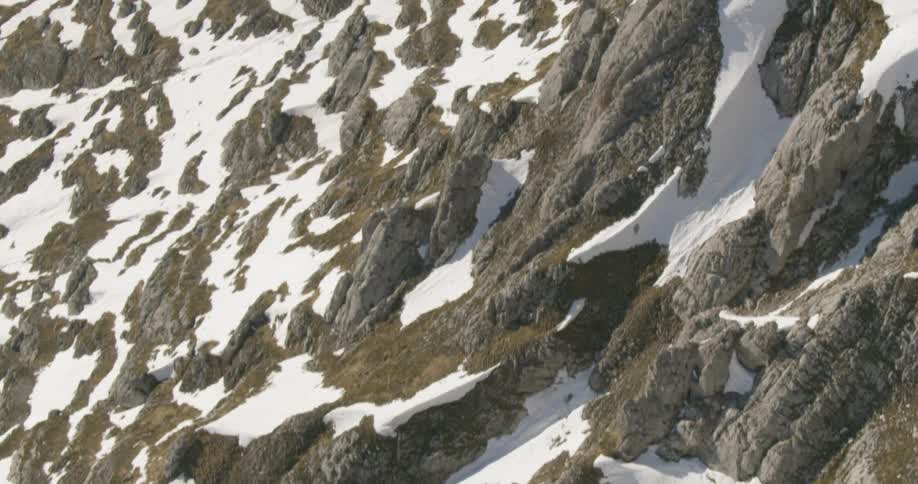 A rocky mountain covered in snow in the daytime