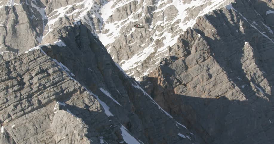 Helicopter hovers near peak of snow covered mountain