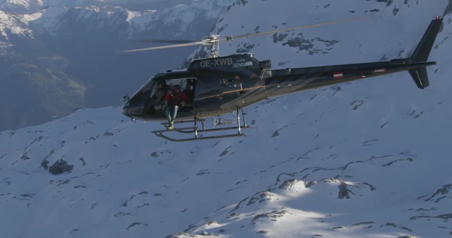 Cameraman films mountain side as pilot flies helicopter backward