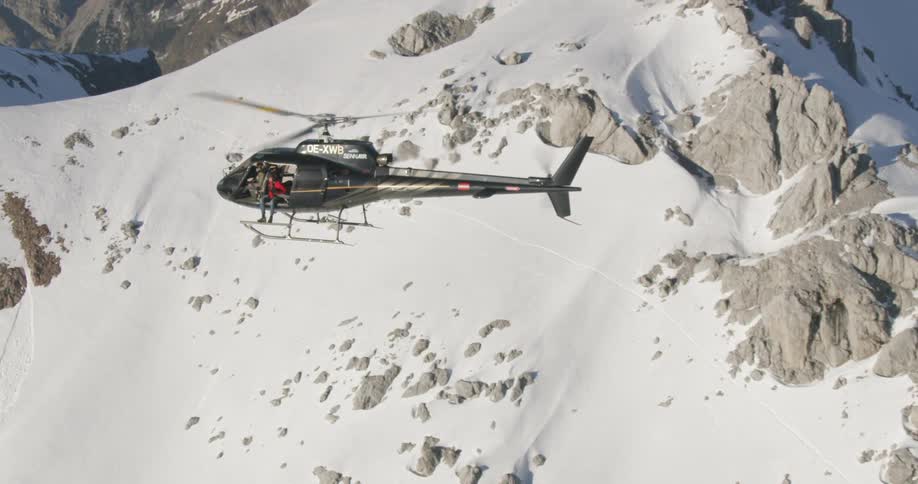 A helicopter is flying over a mountain in winter