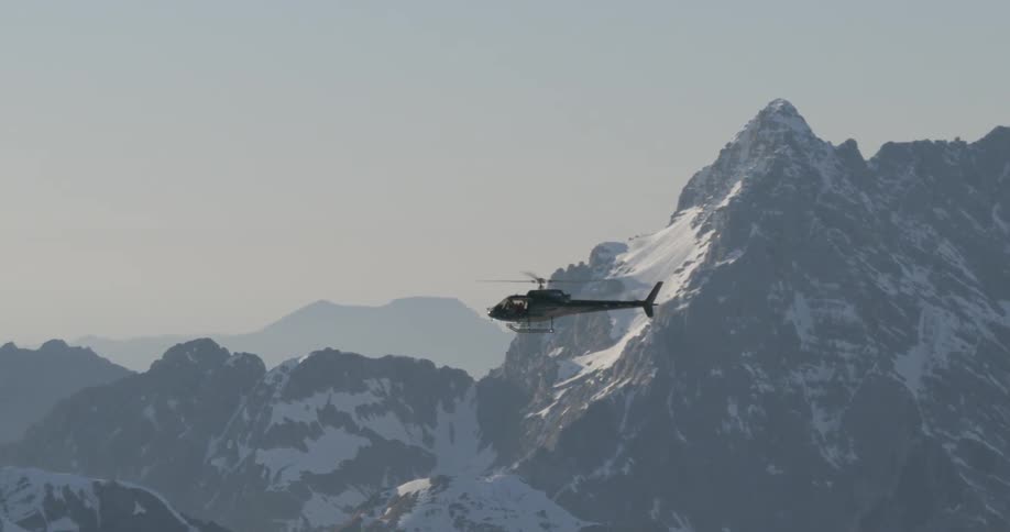 A helicopter flying in the sky with mountains in the background