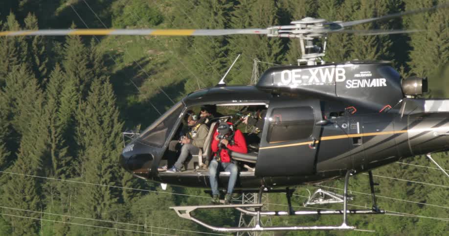 Photographer hanging out of helicopter taking aerial pictures of the forest