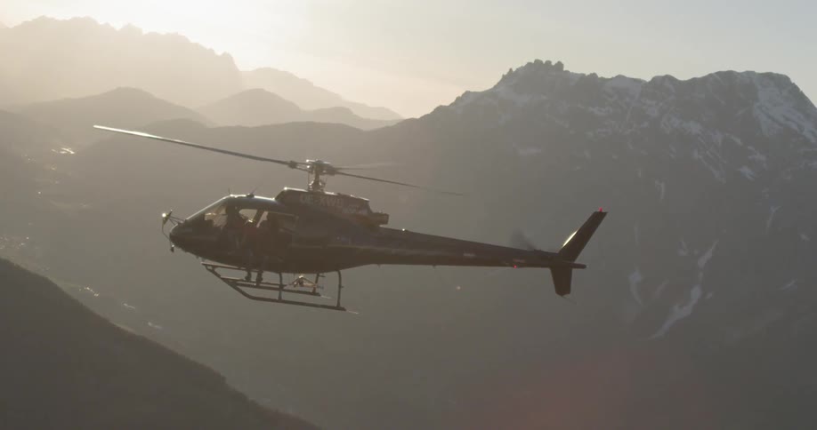 A helicopter is hovering above the foggy mountain range
