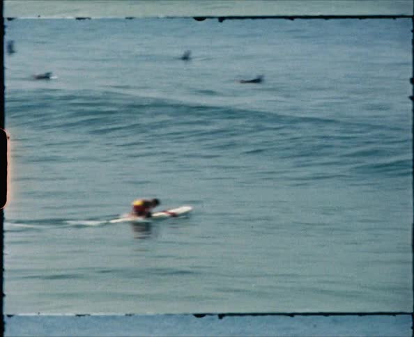 Surfer paddles out to sea on surfboard