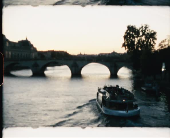 A tour boat filled with people motors to an arched bridge