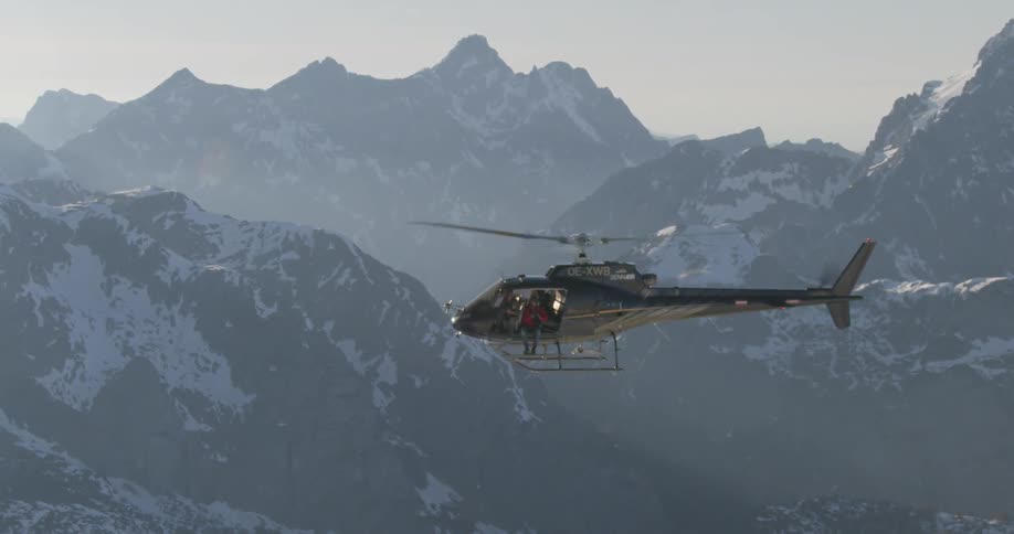 A person is riding a helicopter over the mountain range