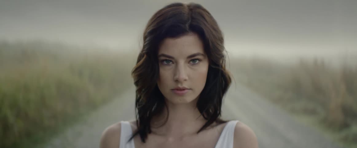 A woman standing on a dirt road staring