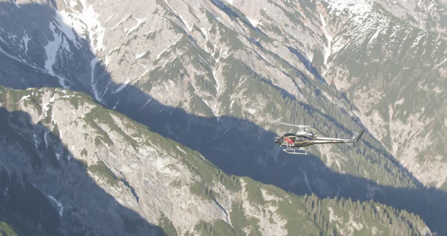 A helicopter flies over mountians