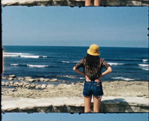A woman is standing on the beach on a windy day