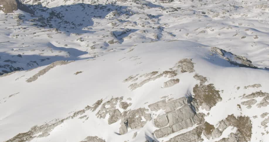 Snow covers a large portion of a rocky and mountains expanse of nature