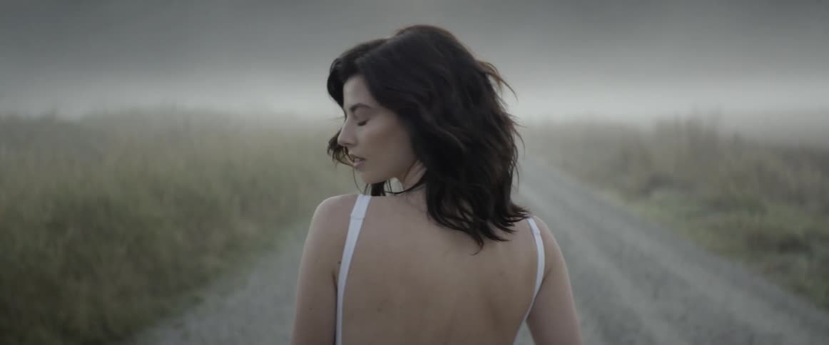 Woman in white dress walks on the country road in fog